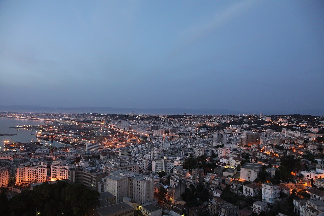 The Bay of Algiers at dusk, with the port and city lights along the coast