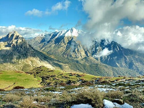 Snow on the peaks of the Djurdjura mountains above green slopes